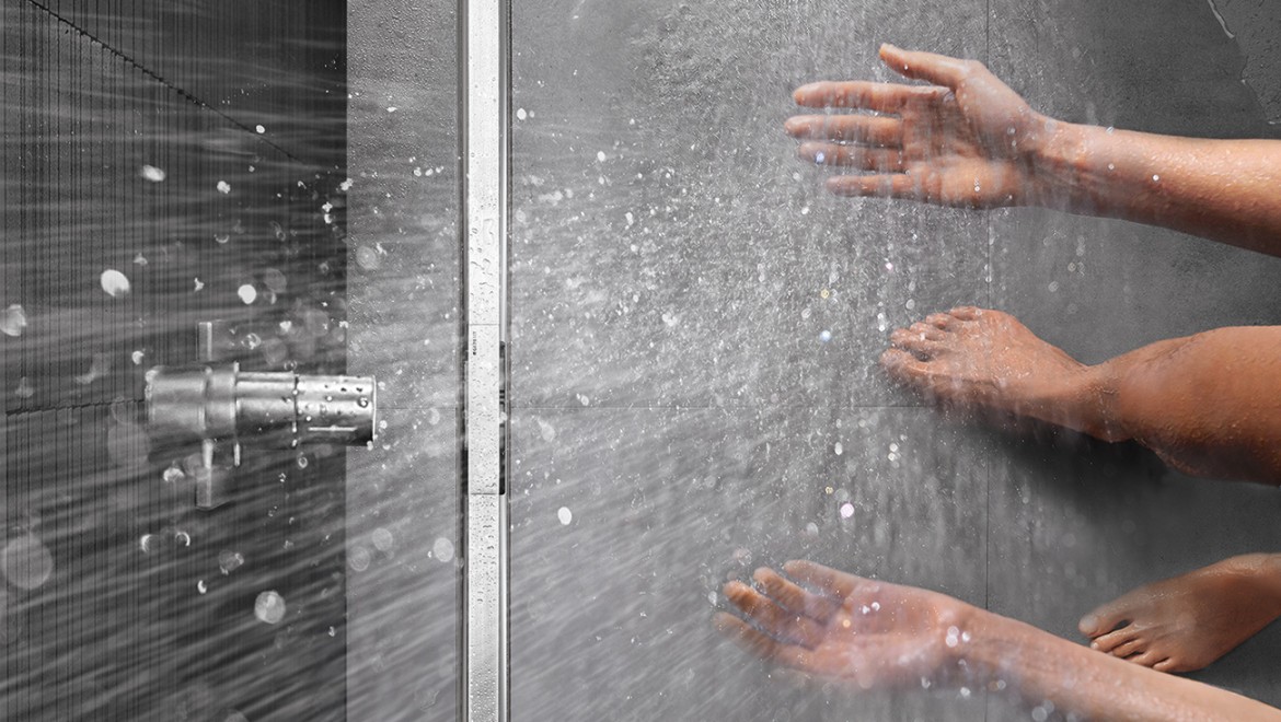 Persoană care face duş într-un duş la nivel de pardoseală dotat cu rigolă de duş Geberit CleanLine
